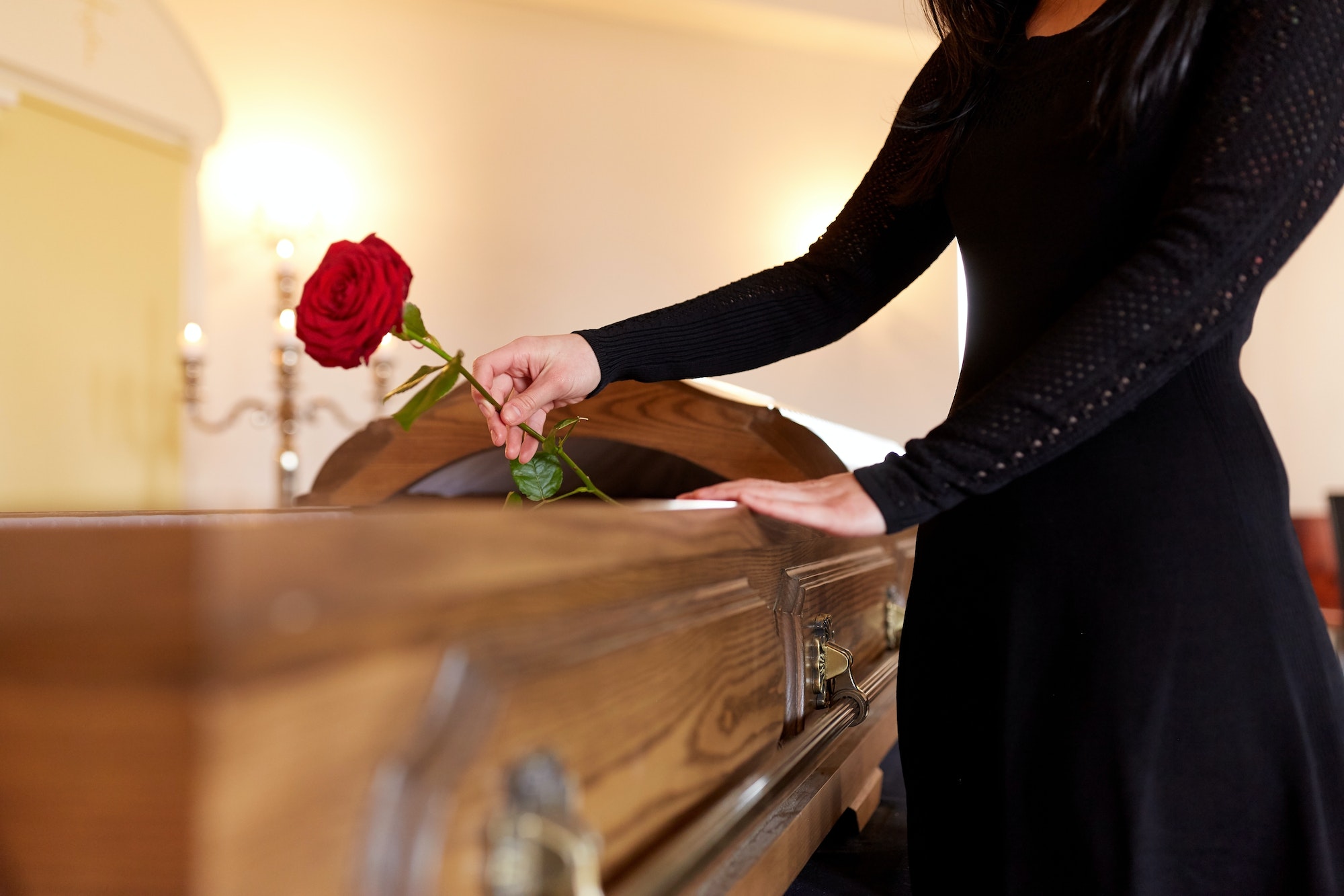 woman with red roses and coffin at funeral